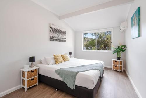 a white bedroom with a bed and a window at Coal and Candle by Beach Stays in Berowra