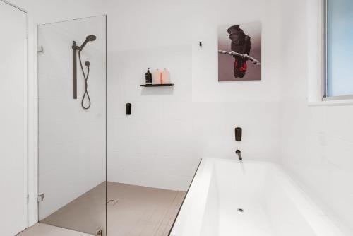 Baño blanco con cabina de ducha de cristal en Coal and Candle by Beach Stays en Berowra