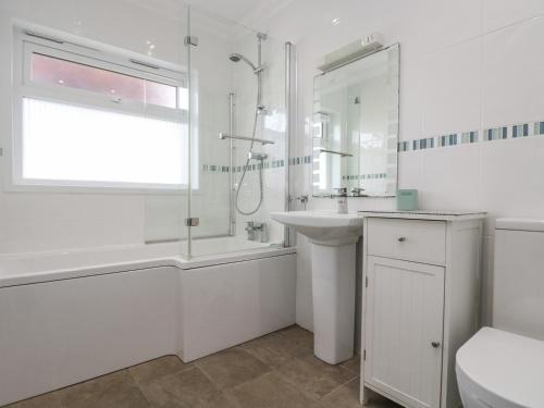 a white bathroom with a tub and a sink and a shower at Polkerris View in St Austell