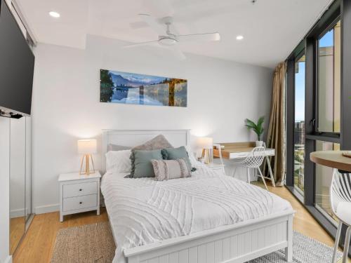 a white bedroom with a bed and a desk at Brand-New Central Studio Apart with Views in Brisbane