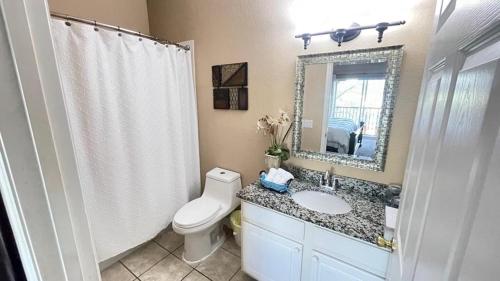 een badkamer met een toilet, een wastafel en een spiegel bij Beautiful 3 Bedroom Apartment minutes from Disney! in Kissimmee