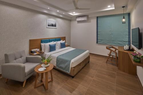 a hotel room with a bed and a chair and a desk at Regenta Inn 4th Block Koramangala Bangalore in Bangalore