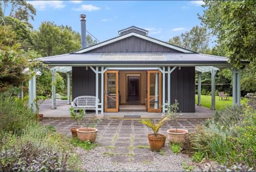 Cabaña negra con porche y banco blanco en The Ponds on Greenhill, en Waikanae