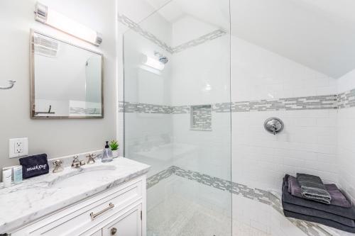 La salle de bains blanche est pourvue d'une douche et d'un lavabo. dans l'établissement Modern Tudor Style Carriage House - Patio & grill, à Ann Arbor