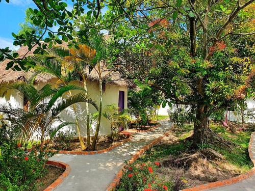 un chemin menant à une maison plantée d'arbres et de fleurs dans l'établissement Bohemiaz Resort and Spa Kampot, à Kampot