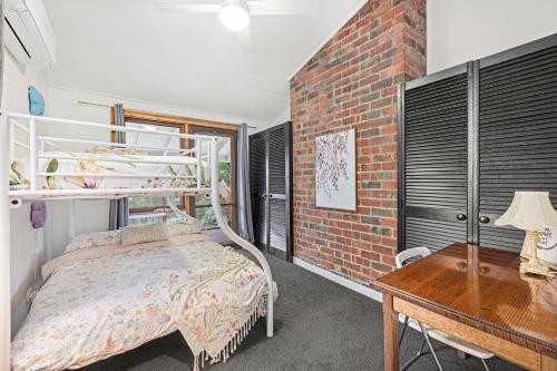 a bedroom with a bunk bed next to a brick wall at Sherbrooke Forest Retreat - Noonameena Home in Sherbrooke