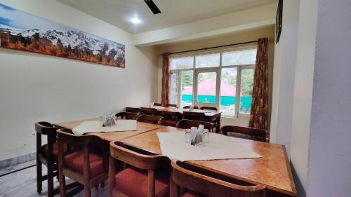 a dining room with tables and chairs and a window at Gagan Resorts in Dharamshala