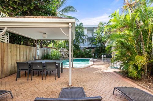 a patio with a table and chairs and a pool at Coral Horizons - Beachfront apartments in Palm Cove