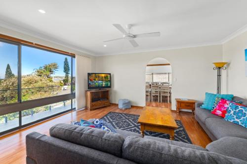 a living room with a couch and a tv at Lentara Street 8 in Fingal Bay