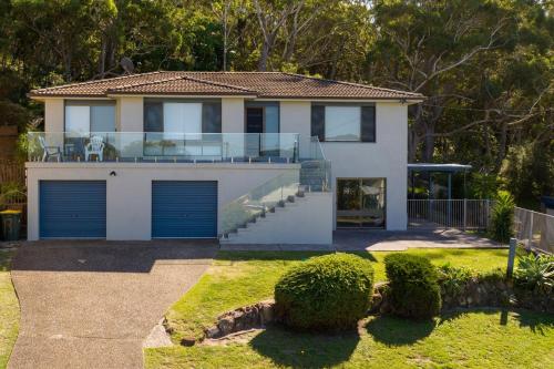 a house with blue garage doors in a yard at Lentara Street 8 in Fingal Bay