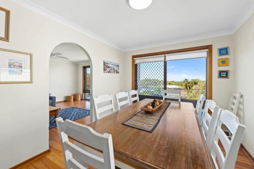 a dining room and living room with a table and chairs at Lentara Street 8 in Fingal Bay