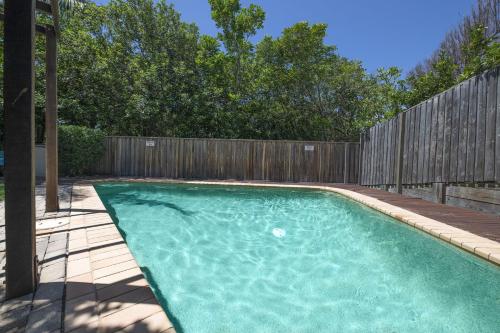 a swimming pool in a backyard with a wooden fence at Parkside on Plover Street in Peregian Beach