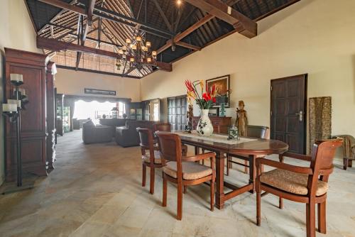 Un comedor con mesa y sillas de madera. en Villa Bukti Paradise- Captivating Beachfront Villa, en Kubutambahan