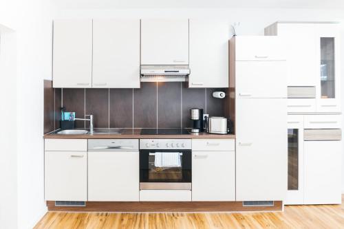a white kitchen with white cabinets and appliances at HEIMATEL - Suiten, Apartments und Studios in Scheidegg