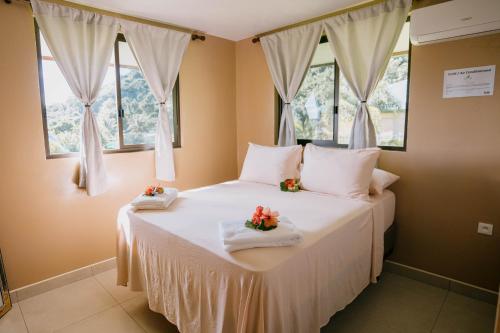a bedroom with a large white bed with two windows at Vue imprenable sur le lagon de Bora Bora in Bora Bora