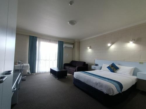 Habitación de hotel con cama y sofá en Admiral Nelson Motor Inn, en Nelson Bay