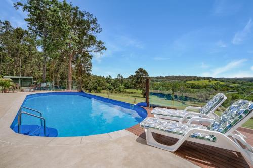 a swimming pool with two lounge chairs next to it at Gympie Luxury Caravan with ensuite bathroom in Tamaree