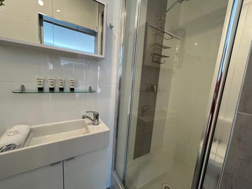 baño blanco con ducha y lavamanos en Vaby s 1, en Jindabyne