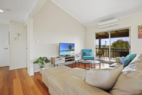 a living room with a couch and a tv at 37 on Gouldian Court Peregian Beach in Peregian Beach