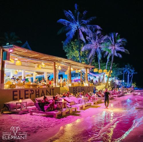 a beach with a bunch of chairs and people on it at Elephant Beach Club & Resort Samui in Chaweng