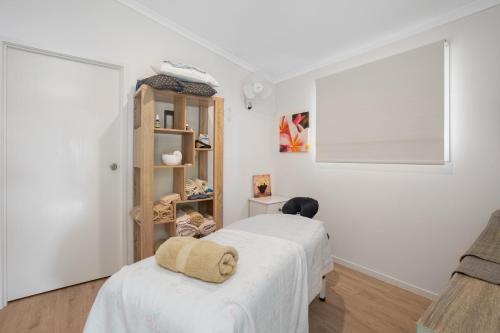 Dormitorio blanco con cama y estante de libros en Gympie Luxury Caravan Stay, en Tamaree