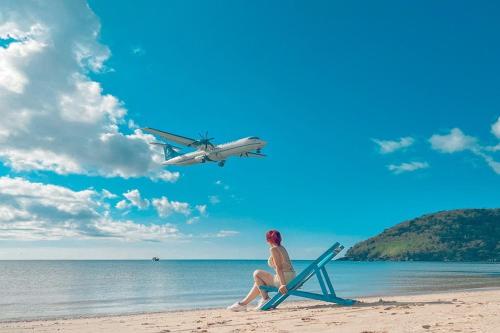 a woman sitting in a chair on a beach with an airplane at Phuc Con Son Hotel in Con Dao