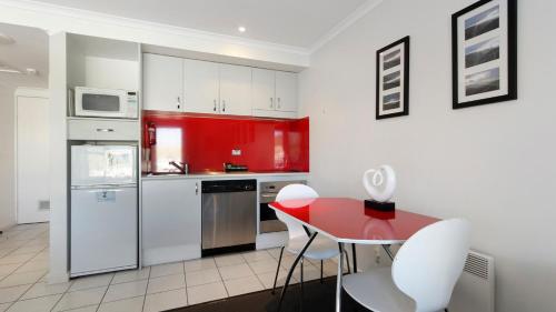 a kitchen with white cabinets and a red table and chairs at White Crystal 112 in Mount Hotham