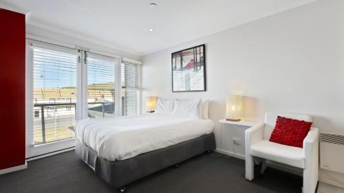 a bedroom with a bed and a chair and a window at White Crystal 112 in Mount Hotham