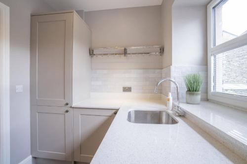 une cuisine blanche avec un évier et une fenêtre dans l'établissement Brand New 4 bedroom 4 bathroom home by LetMeStay, à Ambleside