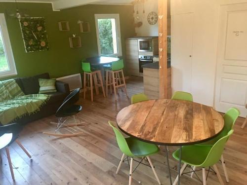 sala de estar con mesa de madera y sillas verdes en Superbe gîte au bord de l’eau, Marais Audomarois en Serques
