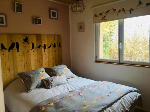 1 dormitorio con cama y ventana con pájaros en la pared en Superbe gîte au bord de l’eau, Marais Audomarois en Serques
