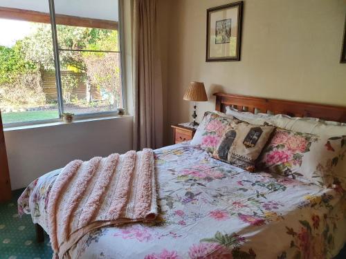 een slaapkamer met een bed met een bloemdekbed en een raam bij Belmont Homestead in Swansea