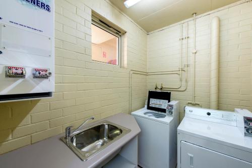 a small bathroom with a sink and a washing machine at Quality Hotel Bayswater in Perth