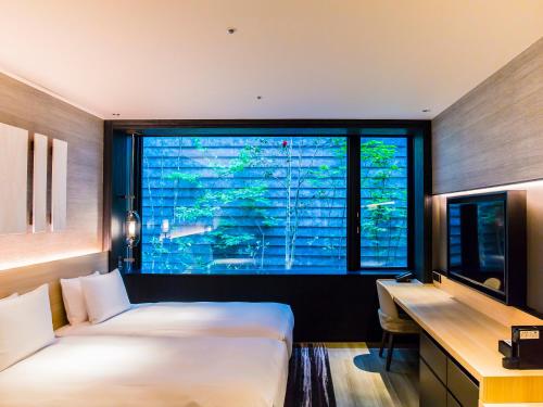 a bedroom with two beds and a desk and a window at Hyatt Place Kyoto in Kyoto