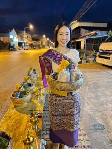 a woman is holding a basket of food at โรงแรมพณิชาวิลล์ 
