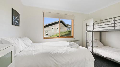 a white bedroom with a bunk bed and a window at Alpine Haven 5 in Mount Hotham