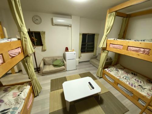 a room with three bunk beds and a table at パインツリー in Matsuyama