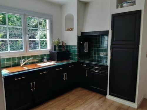 - une cuisine avec des placards noirs et un évier dans l'établissement Maison cocooning près du centre d'Avignon, à Avignon