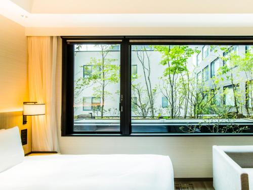 a bedroom with a window looking out at a city at Hyatt Place Kyoto in Kyoto