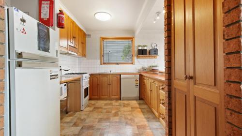 荷斯安山的住宿－Alpine Haven 1，厨房配有木制橱柜和白色冰箱。