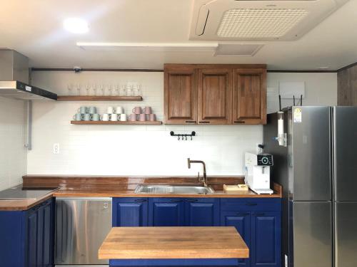 uma cozinha com armários azuis e um frigorífico de aço inoxidável em Cheukhu-dong 19street Guesthouse em Mokpo