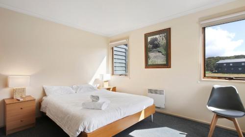 a bedroom with a bed and a chair and a window at Breck in Dinner Plain