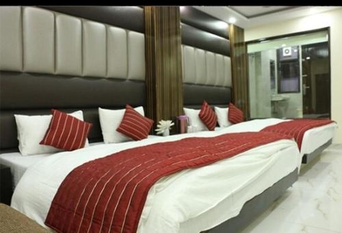 a bedroom with a large bed with red and white pillows at hotel Priya Palace BY BYOB Hotels in New Delhi