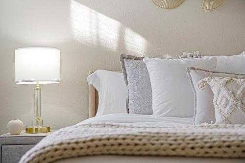 a bed with white pillows and a lamp on a table at Designer Apt w Jacuzzi Walk To Casino & iMax in Sparks