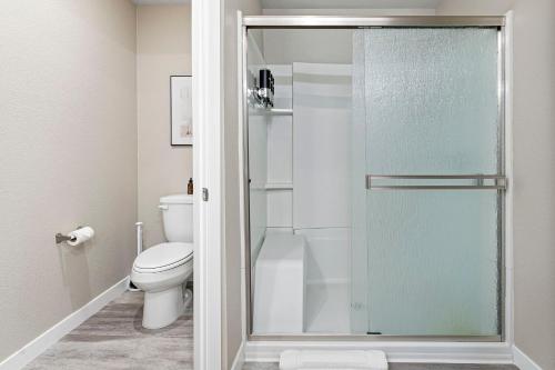 a bathroom with a toilet and a glass shower door at Designer Apt w Jacuzzi Walk To Casino & iMax in Sparks