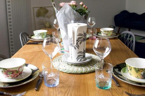 une table en bois avec des assiettes et des verres à vin dessus dans l'établissement Très Belle MAISON à Rennes St Jacques, à Saint-Jacques-de-la-Lande