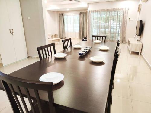 uma sala de jantar com uma grande mesa de madeira e cadeiras em Puchong Landed Homestay - 2nd unit @ BKT Puchong em Puchong