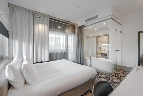 a bedroom with a white bed and a glass shower at Qubus Hotel Bydgoszcz in Bydgoszcz