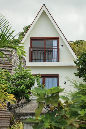 a white house with red windows and plants at Kabeh Jati Garden Villa & Restaurant in Nusa Penida