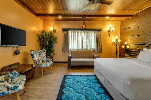 a bedroom with a bed and a couch and a tv at The Baga Beach Resort in Baga